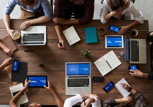 Overhead view of a diverse team in a business meeting using laptops and tablets.