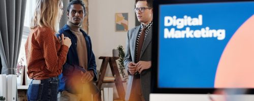 Group of colleagues discussing digital marketing strategies in an office setting.